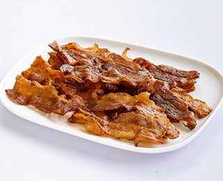 Tiras de bacon frito sobre un plato.