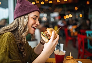 Una chica comiendo una hamburguesa de frijol para conseguir macronutrientes