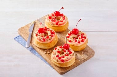 Donas decoradas con crema, cerezas en almíbar y trozos de nuez