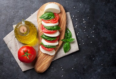 Ensalada caprese con aceite de oliva y un par de hojas de albahaca en toma cenital