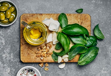 Albahaca, queso feta, aceite de oliva y otros ingredientes para preparar una ensalada mediterránea