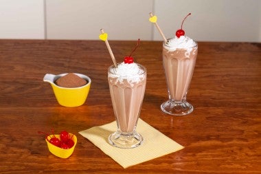 Malteada de chocolate decorada con crema batida y cerezas en almíbar