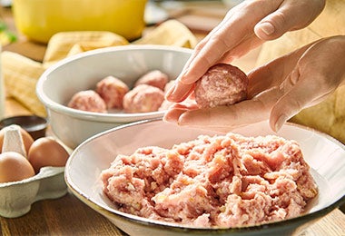 Mujer armando albóndigas con migas de pan para dar estructura y forma