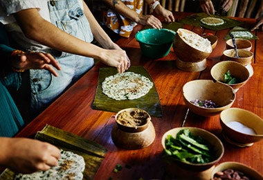 Mujeres armando tamales en hojas de plátano