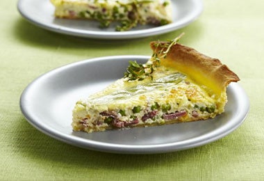 Porción de pastel de pescado servido en un plato sobre un mantel verde