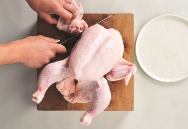 Despiece del pollo sobre tabla de madera, separando las partes para preparar chicharrón de pollo