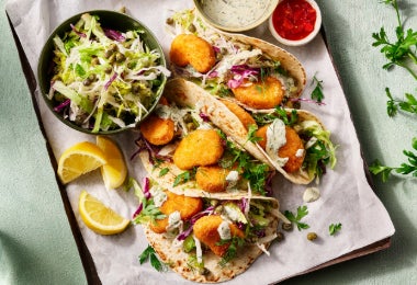 Tacos de chicharrón de pollo, acompañados de col fresca y salsas con rodajas de limón