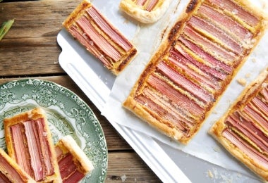 Tarta de ruibarbo con tiras rosadas alineadas, servida en una bandeja