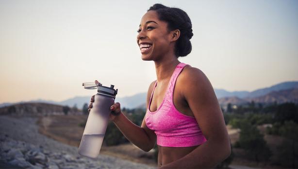 Mujer haciendo deporte e hidratándose con botella reutilizable