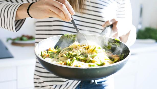 Una persona cocinando su comida con menos de 5 ingredientes en una sartén