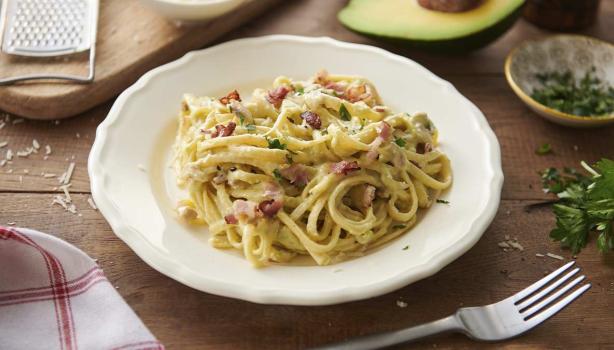 Pasta carbonara con pollo, tocineta y hierbas en un plato hondo