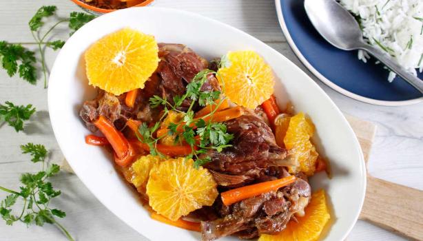 Plato de cerdo con salsa de naranja, acompañado de rodajas de naranja