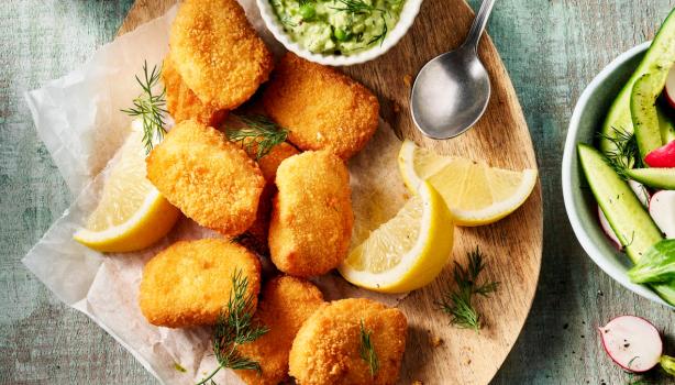 Trozos de chicharrón de pollo crujiente servidos con salsa verde, rodajas de limón y ensalada fresca